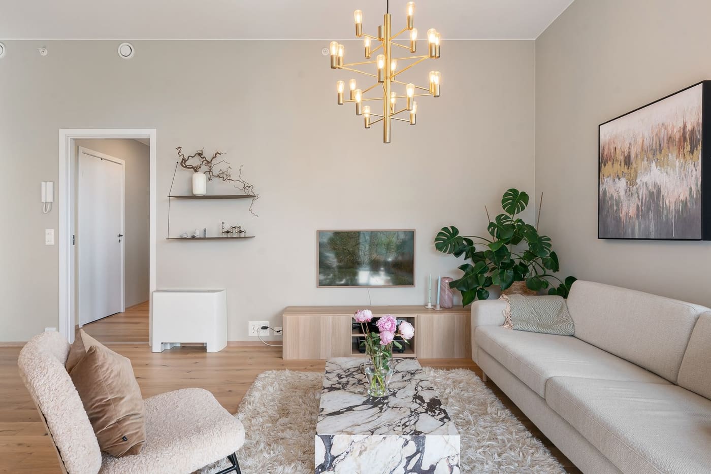 A bright living room with a neutral sofa, pale walls, and a few simple decor pieces