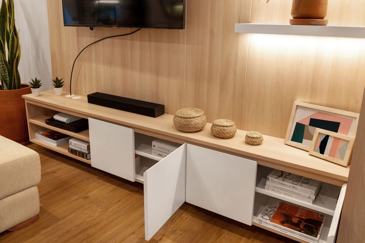 A wood-toned media console with open shelves and woven baskets holding small items