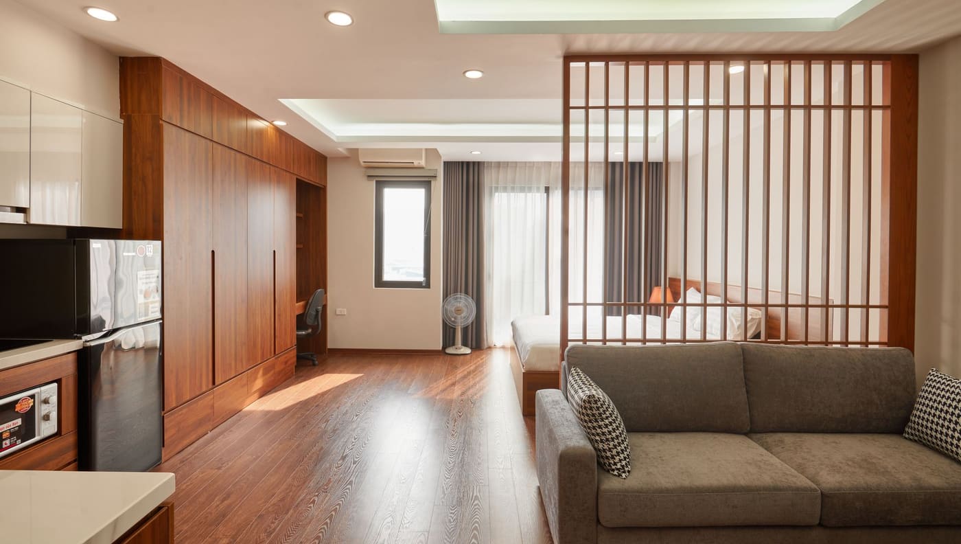A studio apartment with a slatted wooden divider separating the bed from the sofa area